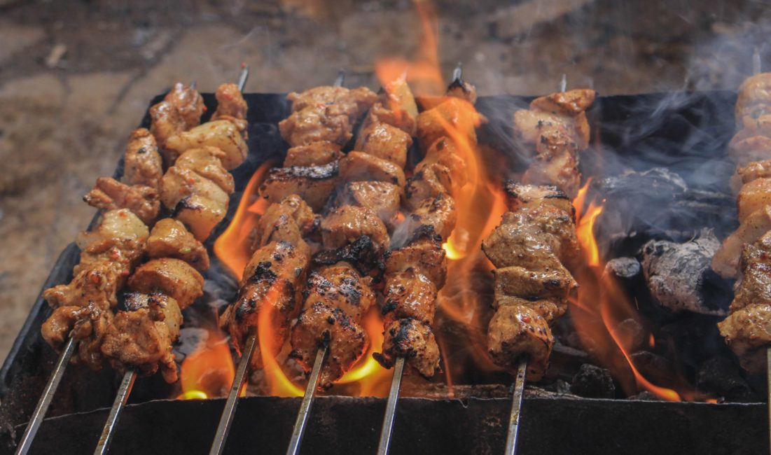 grilled meat on skewers over charcoal grill flames