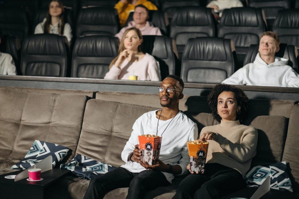 man and woman eating popcorn in movie theater