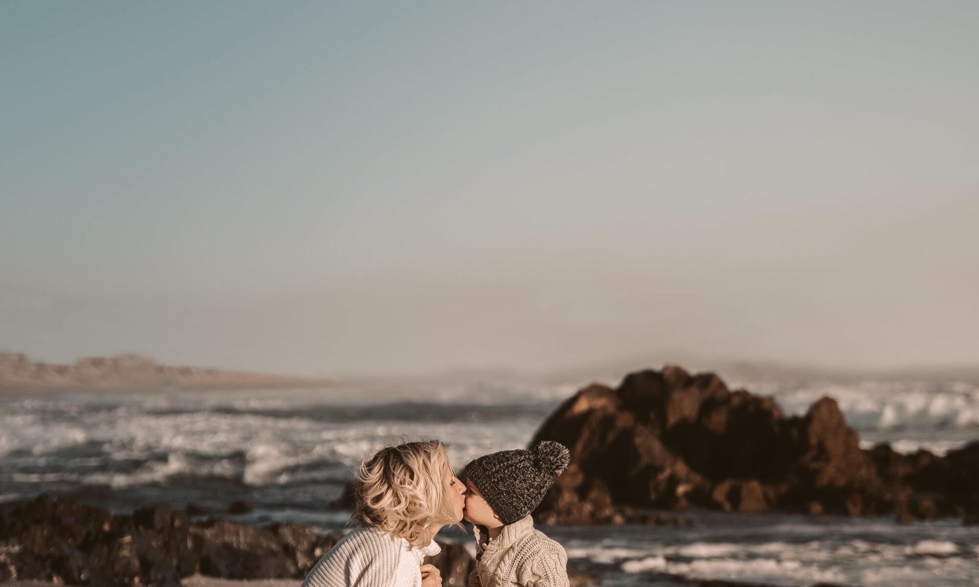 woman embracing toddler on beach newport beach getaways resolution blog